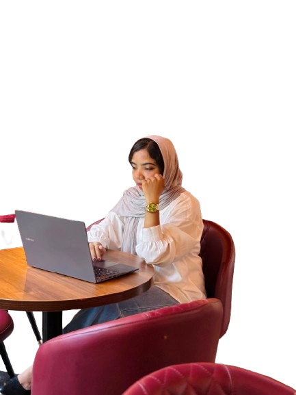 A woman sitting at a table, working on her laptop